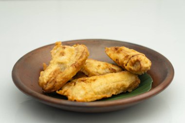 Yeşil yapraklı kil tabakta servis edilen kızarmış muzlar.