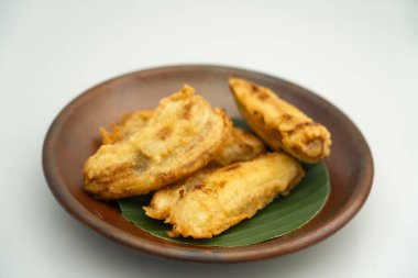 Yeşil yapraklı kil tabakta servis edilen kızarmış muzlar.