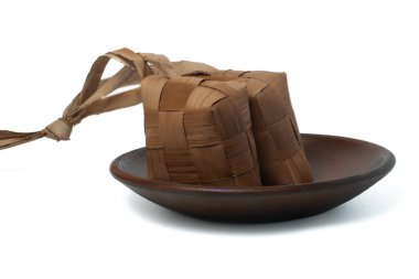 Beyaz arka planda çömlek tabağında ketupat ya da pirinç köftesi.