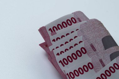 100.000 Rupiah Endonezya banknotları düzgünce istiflenmiş ve beyaz bir zemin ile kıvrılmış.