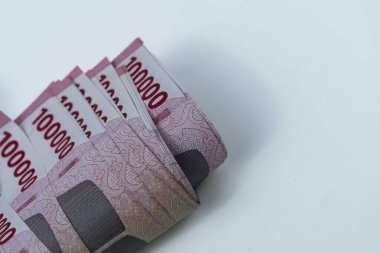 100.000 Rupiah Endonezya banknotları düzgünce istiflenmiş ve beyaz bir zemin ile kıvrılmış.