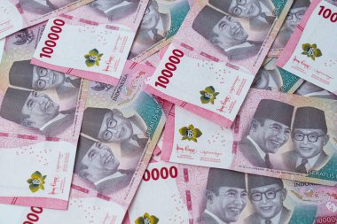 100.000 Rupiah Endonezya banknotları beyaz bir yüzeye yayıldı. Notlarda Soekarno ve Mohammad Hatta 'nın resimleri yer alıyor..