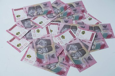 100.000 Rupiah Endonezya banknotları beyaz bir yüzeye yayıldı. Notlarda Soekarno ve Mohammad Hatta 'nın resimleri yer alıyor..