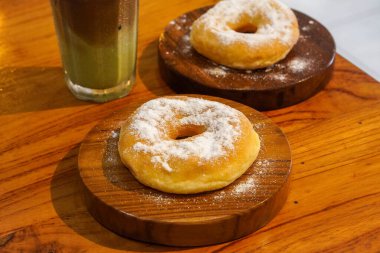 1 Şubat 2025 'te yakalanan taze pişmiş çörekler ahşap bir masanın üzerinde iyi şekerle tozlandı. Altın kahverengi dokular ve tatlı kaplamalar karşı konulmaz, ağız sulandırıcı bir ziyafet yaratıyor.