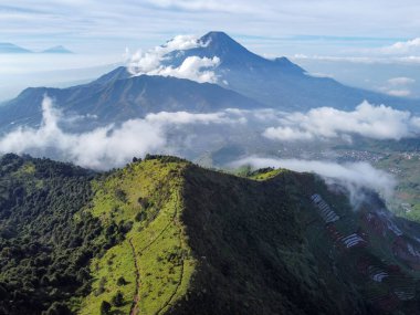 Endonezya 'nın merkezindeki Prau Dağı' nın havadan görüntüsü 28 Nisan 2025 'te çekildi. Yuvarlanan yeşil tepeler ve sisli tepeler berrak mavi gökyüzünün altında çarpıcı bir doğal manzara yaratır.