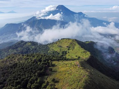 Endonezya 'nın merkezindeki Prau Dağı' nın havadan görüntüsü 28 Nisan 2025 'te çekildi. Yuvarlanan yeşil tepeler ve sisli tepeler berrak mavi gökyüzünün altında çarpıcı bir doğal manzara yaratır.