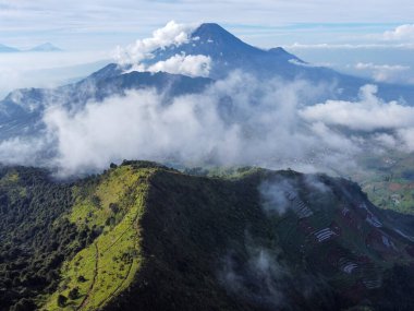 Endonezya 'nın merkezindeki Prau Dağı' nın havadan görüntüsü 28 Nisan 2025 'te çekildi. Yuvarlanan yeşil tepeler ve sisli tepeler berrak mavi gökyüzünün altında çarpıcı bir doğal manzara yaratır.