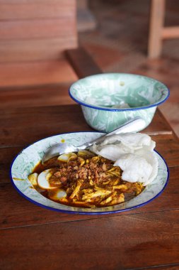 Lontong kari ayam, Endonezya, 2 Ağustos 2025 'te yakalandı. Baharatlı tavuk, hindistan cevizi çorbası ve geleneksel Endonezya kahvaltısı favorisi aromalı otlarla servis edilen pirinç kekleri..