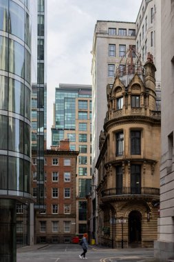 Aynalı cam panelleri ve klasik İngiliz tarzı tuğla binaları olan modern bir bina da dahil olmak üzere, mimarinin bir karışımının yer aldığı dar bir kentsel sokak..