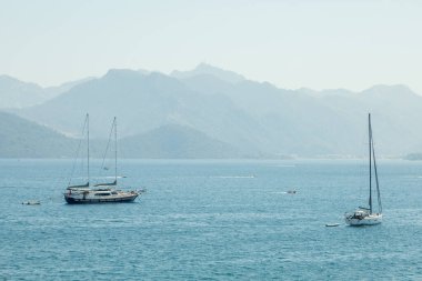 Marmaris 'in sakin sularında yüzen yelkenliler büyüleyici doğal güzelliklerin ortasında.