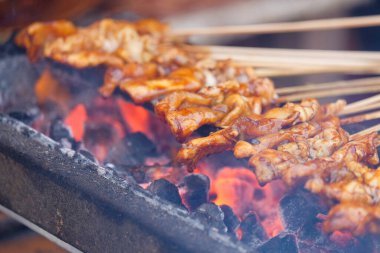 Ahşap kömür kullanarak ızgara tavuk satay. Tipik Endonezya tavuğu pişirme süreci. Soya sosu yüzünden kapalı tavuk satay kahverengisi.
