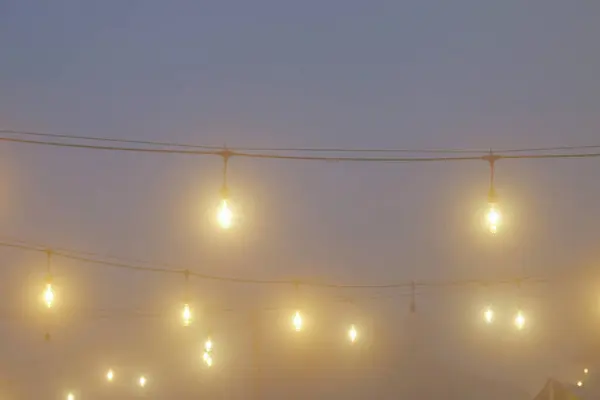 Garden lights on a foggy night. The lights look dim in the night fog. The light looks dramatic
