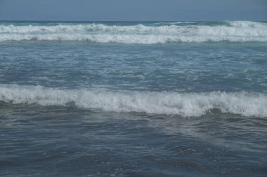 Mavi bir arka planda, deniz dalgalarının soyut şekilleri, desenleri ve dokuları. Gün boyunca denizde yüksek dalgalar. Grafik tasarımı veya afiş arkaplanı için