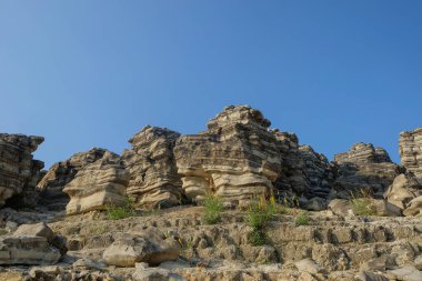 Mavi gökyüzü arka planlı kireçtaşı tepelerin manzarası. Soyut şekilleri, desenleri ve dokuları olan kireçtaşı tepelerin manzarası. Grafik tasarımı için şık ve estetik görünüyor.