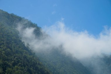 Tepelerin ötesindeki beyaz bulutların görüntüsü. Gün boyunca tepenin manzarası. Tepeler ve bulutlar mavi gökyüzü arka planında