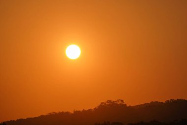 Gün batımında yuvarlak güneş ve altın sarısı gökyüzü. Öğleden sonra güzel bir gökyüzü manzarası. Afiş arkaplan ya da grafik tasarımlar için. Kırsalda gün batımı. Boşluğu kopyala