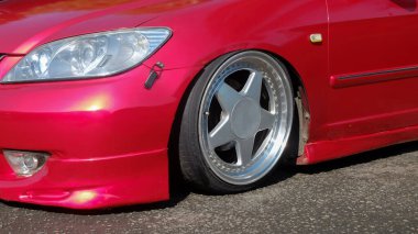 Kırmızı araba lastiklerinin ve jantların modifikasyonu. Ön lastikler arabanın tamponuna çok yakın. Araba bileşenlerindeki değişimler