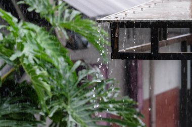 Şiddetli yağmurda evin çatısından yağmur damlaları yağar. İklim ve hava durumu. Su damlacıklarını kapat.