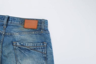 Boş kahverengi deri çerçeveli mavi kot pantolon izole edilmiş beyaz arka plan. Giysi endüstrisi kavramı. Grafik tasarımı veya afiş arkaplanı için metin alanı kopyala