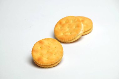 Beyaz arka planda tereyağlı ve kremalı kraker bisküvileri. Tatlı ve çıtır çıtır bir tat. Yemek endüstrisi kavramı. Grafik tasarımı veya afiş arkaplanı için alanı kopyala.