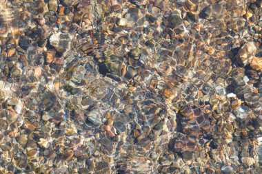 Üst manzara deseni ve berrak su dalgalanmalarının dokusu. Doğal dokulu arka plan. Görünür nehir yatağı kayalar. Grafik tasarımı veya afiş arkaplanı için