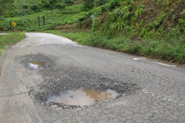Tepelerdeki asfalt yolda çukurlar hasar görmüş ve su basmış. Altyapı ve ulaşım kavramı. Grafik tasarımı için, 3D tasarım ve afiş arkaplanı