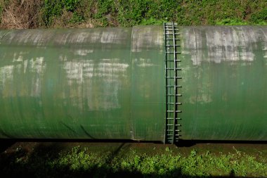 Elektrik santrallerine su tedarik etmek için kullanılan büyük borulardaki bağlantılar. Büyük yeşil demir borular. Enerji endüstrisi kavramı. Grafik tasarımı, 3D tasarım ve afiş arka planı için