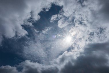 Güneş, koyu gri bulutların arasında parlak bir şekilde parlıyor. İklim ve hava durumu. Grafik tasarımı için, 3 boyutlu görüntüleme ve pankart arkaplanı