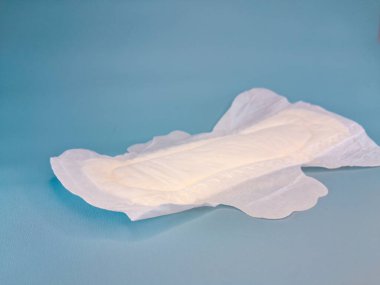 Pamuktan ve diğer doğal malzemelerden yapılmış kan emici pedlerle tek kullanımlık pedler ya da peçeteler, kadınlık ve kadın mahrem organları için hijyen kavramı, mavi arka planda izole edilmiş..
