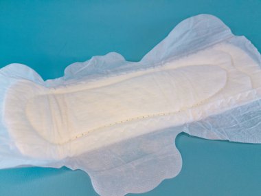Pamuktan ve diğer doğal malzemelerden yapılmış kan emici pedlerle tek kullanımlık pedler ya da peçeteler, kadınlık ve kadın mahrem organları için hijyen kavramı, mavi arka planda izole edilmiş..