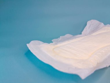 Pamuktan ve diğer doğal malzemelerden yapılmış kan emici pedlerle tek kullanımlık pedler ya da peçeteler, kadınlık ve kadın mahrem organları için hijyen kavramı, mavi arka planda mesaj için negatif alan ile izole edilmiş..