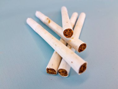 Sağlığa zararlı filtreli pis sigara yığını, solunum sağlığı konsepti, mavi arka planda izole edilmiş.