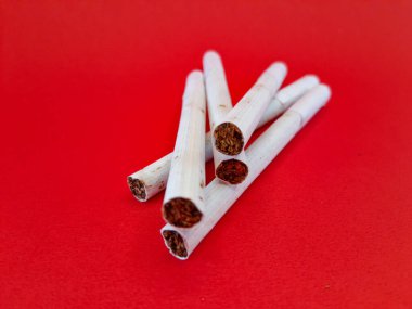 Sağlığa zararlı filtreli pis sigara yığını, solunum sağlığı konsepti, kırmızı arka planda izole edilmiş.