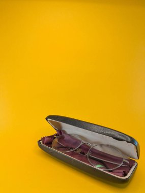 Temizlik bezi, görüş düzeltme gözlüğü ile eksiksiz düzenlenmiş bir kutuda bir gözlük seti, yakın çekim ve izole edilmiş sarı arkaplan ile metin için negatif alan.