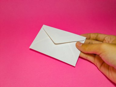 Düz beyaz zarf pembe arka planda kadının elinde, katlanmış zarf modelleme elementi yazışmalar, iş yerleri, doğum günleri ve davetiyeler için..