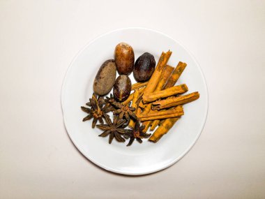 Bir tabakta çeşitli bitki ve baharatların bileşimi, çeşni ve baharatla dolu baharat konsepti, beyaz arka planda izole edilmiş..