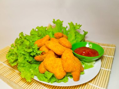 Lezzetli tavuk nugget ve domates sosu marul ya da su teresi ile servis edilmiş, beyaz arka planda izole edilmiş..
