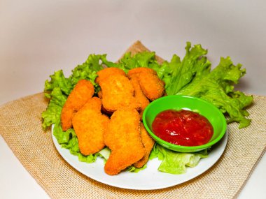 Lezzetli tavuk nugget ve domates sosu marul ya da su teresi ile servis edilmiş, beyaz arka planda izole edilmiş..