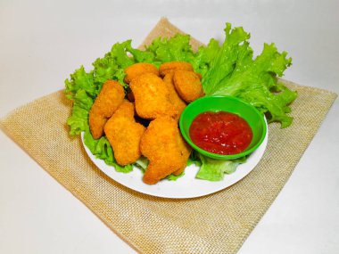 Lezzetli tavuk nugget ve domates sosu marul ya da su teresi ile servis edilmiş, beyaz arka planda izole edilmiş..