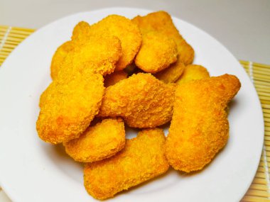 Tabakta servis edilen nefis ekmeklenmiş tavuk nuggetları, beyaz arka planda izole edilmiş..