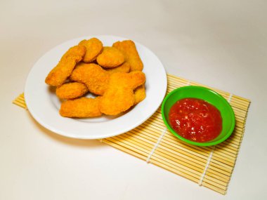Beyaz arka planda izole edilmiş, domates soslu leziz tavuk nuggetları..