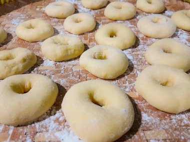 Çiğ çörek hamuru yükseldi ve üzerine buğday unu serpiştirilmedi. Tatlı bir ikram için ev yapımı çörekler..