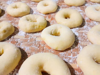 Çiğ çörek hamuru yükseldi ve üzerine buğday unu serpiştirilmedi. Tatlı bir ikram için ev yapımı çörekler..