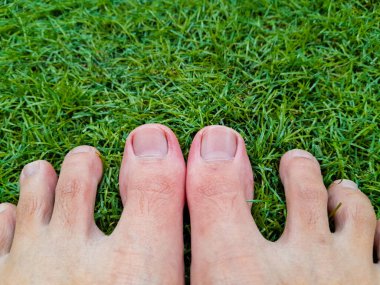 Taze yeşil çimenlerin üzerinde çıplak ayakla rahatlayan bir kadın. sağlıklı ayak konsepti. Doğanın tadını.