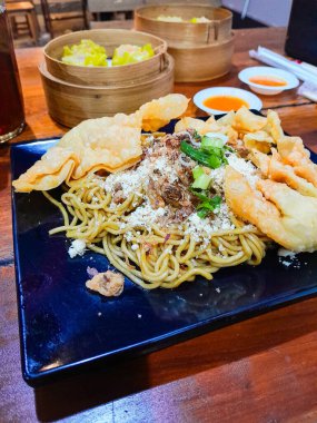 Kızarmış erişteyle kızartılmış mantı ve dilimlenmiş sebzeler. Dim Sum ya da haşlanmış hamur köftesi..