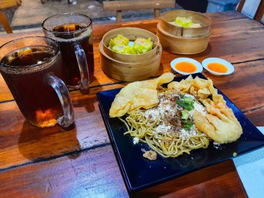 Kızarmış erişteyle kızartılmış mantı ve dilimlenmiş sebzeler. Dim Sum ya da haşlanmış hamur köftesi..