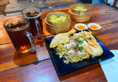 Kızarmış erişteyle kızartılmış mantı ve dilimlenmiş sebzeler. Dim Sum ya da haşlanmış hamur köftesi..