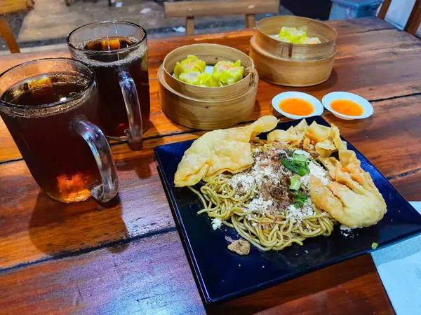 Kızarmış erişteyle kızartılmış mantı ve dilimlenmiş sebzeler. Dim Sum ya da haşlanmış hamur köftesi..