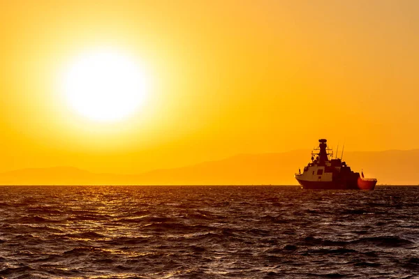 明媚的红色落日的天空笼罩着群山 太阳和北约海军的船只在前方 — 图库照片