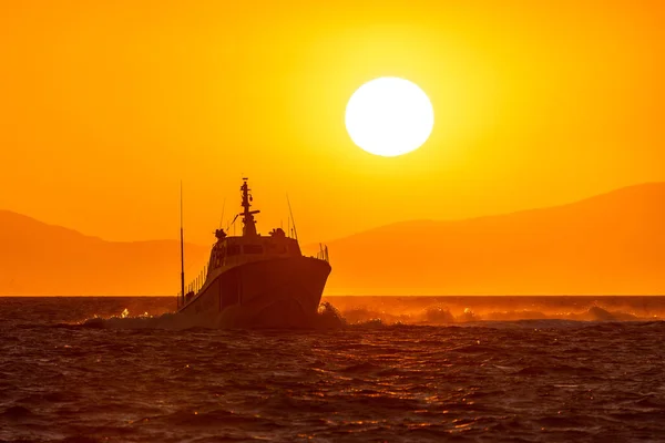 在伊兹密尔市附近的爱琴海中航行的海岸警卫队船 背景为日落的天空和太阳 — 图库照片